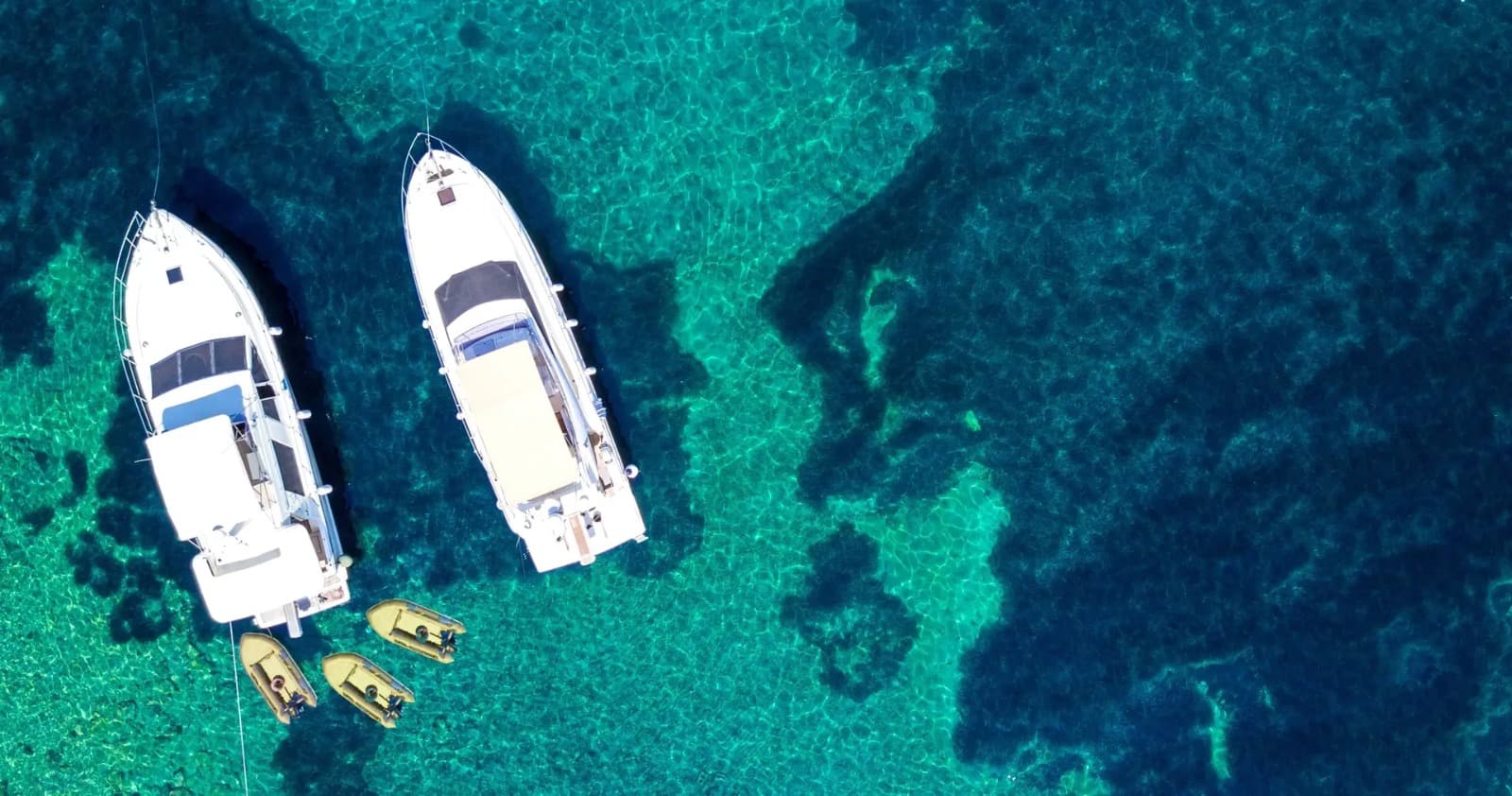 Aerial view of Costa Viva yachts and tender boats anchored above crystal-clear turquoise water